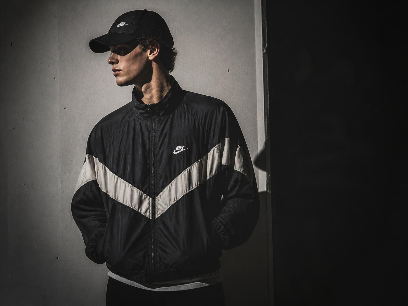 Man wearing a vintage Nike windrunner jacket against a concrete wall